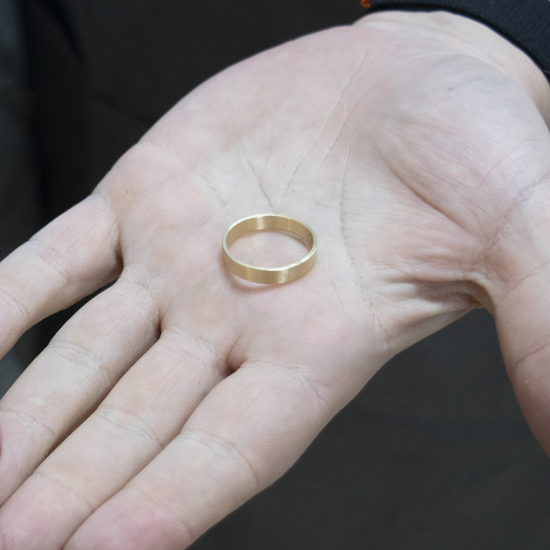 Two hands holding gold rings against a blurred background